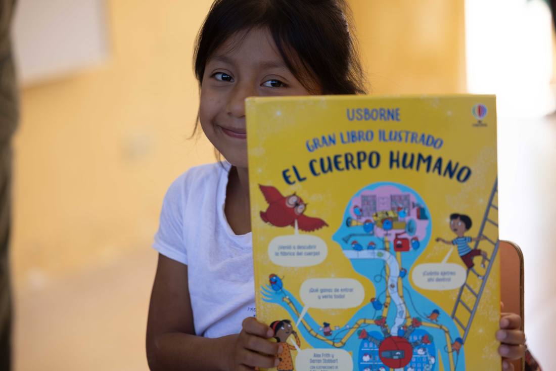 A student proudly holding up an illustrated book