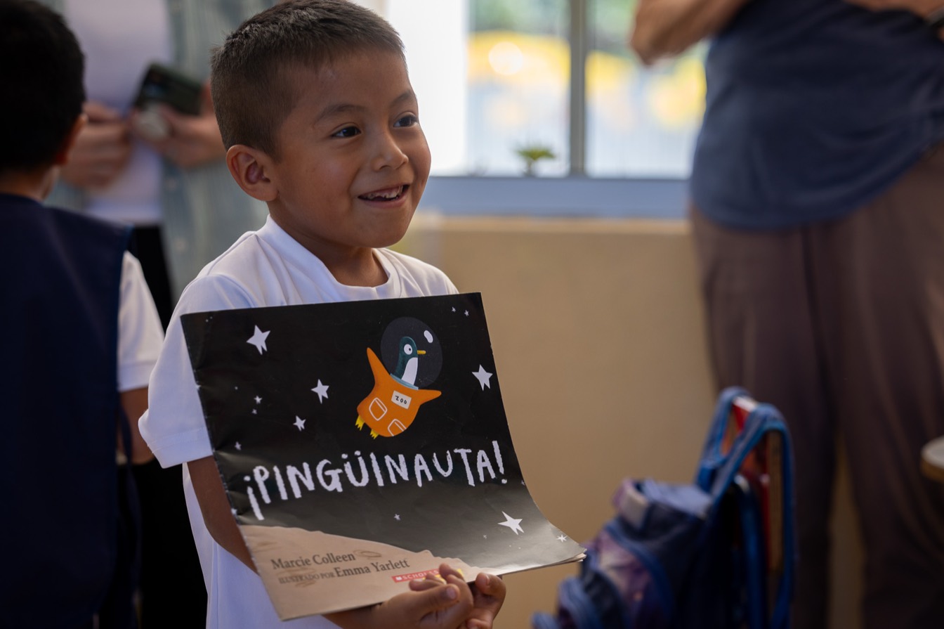 A smiling boy holding the picture book Pinguinauta